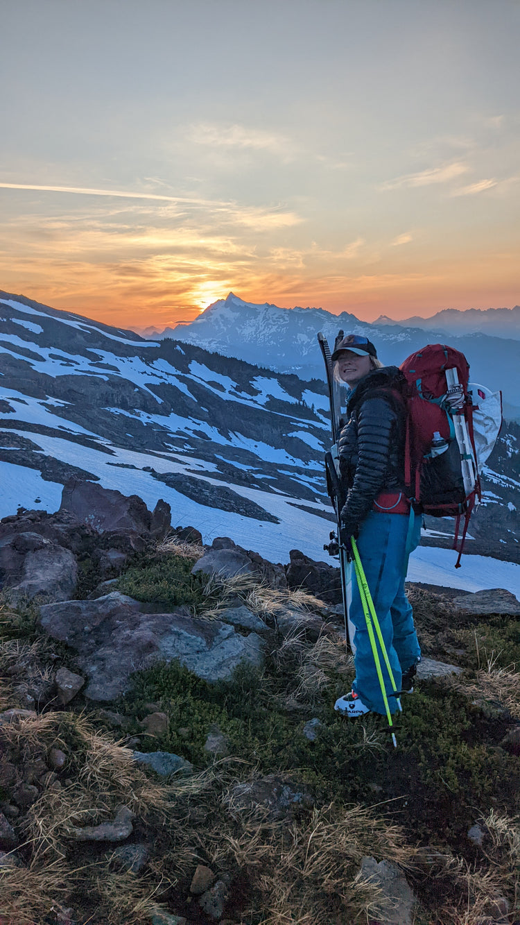 lady with skis and camping backpack on mountain